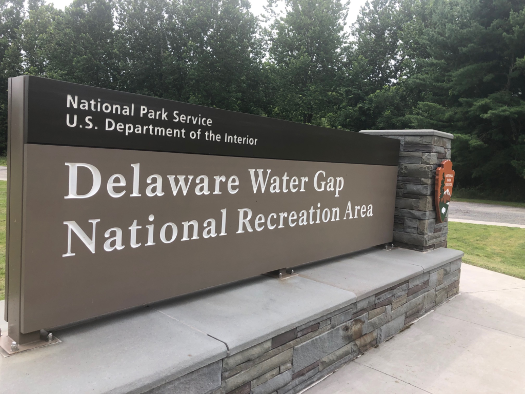 A National Park Service sign for the Delaware Water Gap National Recreation Area on a stone stand.