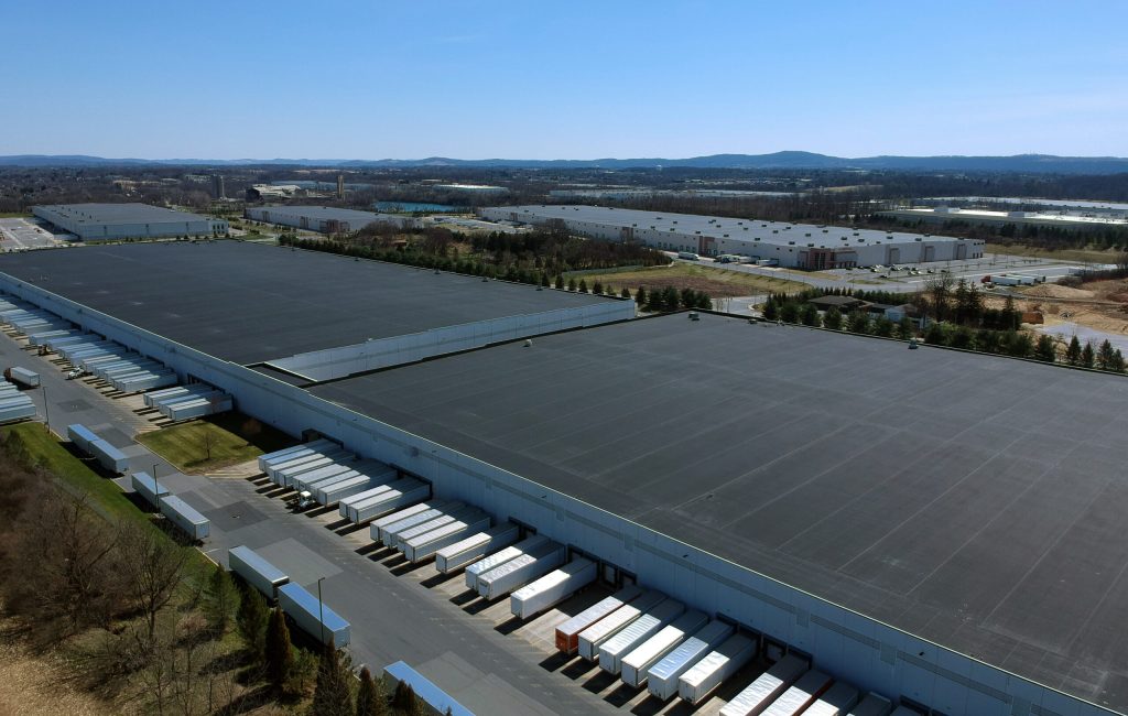 A warehouse with lines of trailers parked along side it. 