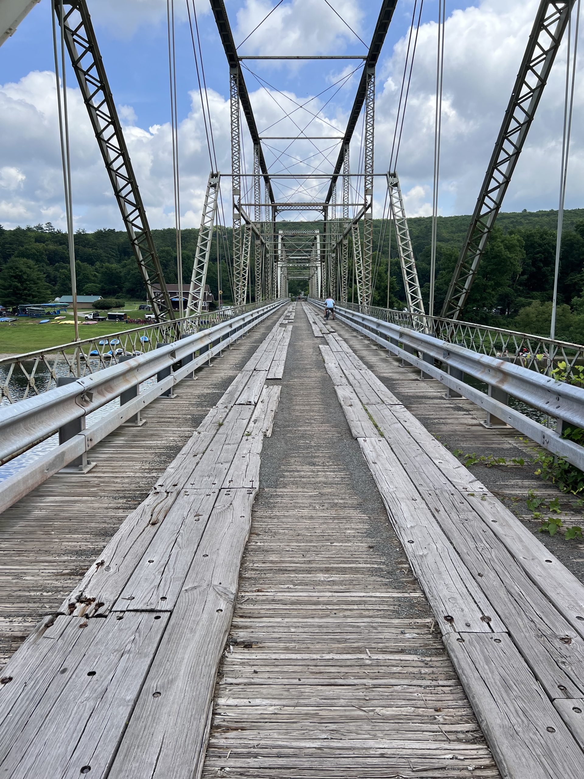 A view of the deck of the Skinners Falls Bridge. Long wooden planks fill the frame.