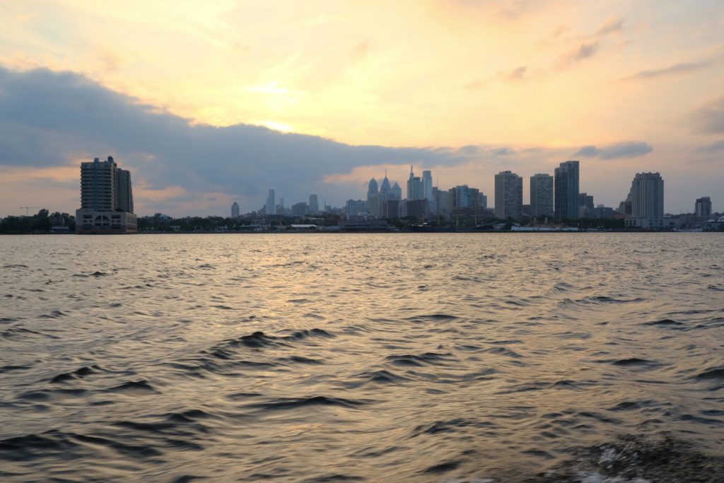 The setting sun peeks over clouds along the Delaware River in Philadelphia. PHOTO BY ADAM LITCHKOFSKI
