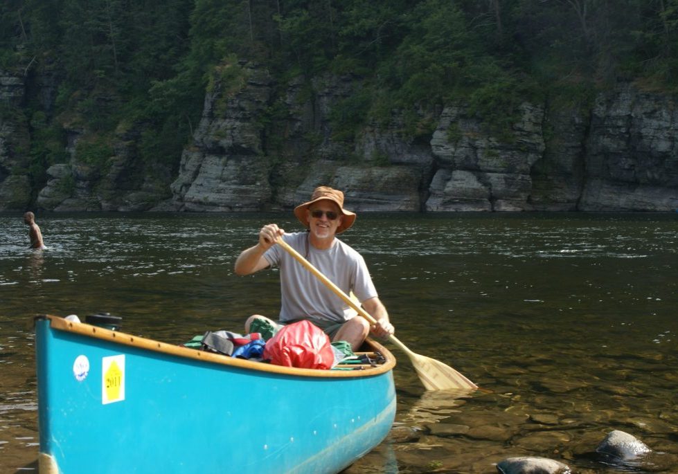 A man in a blue canoe paddling in the Delaware River