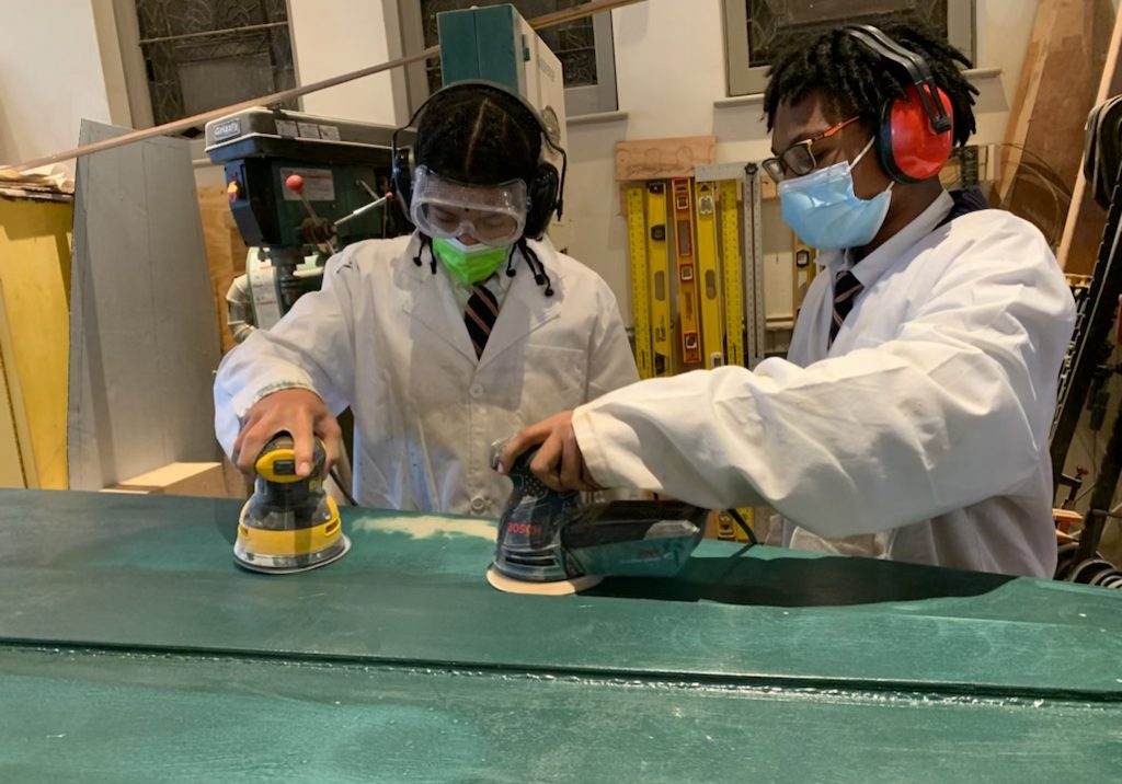 Jeremiah Colman, left, and Zaire Seaberry, UrbanPromise 7th-graders, working on the canoe they’ve been helping to build since the beginning of the school year. PHOTO BY KATHERINE RAPIN