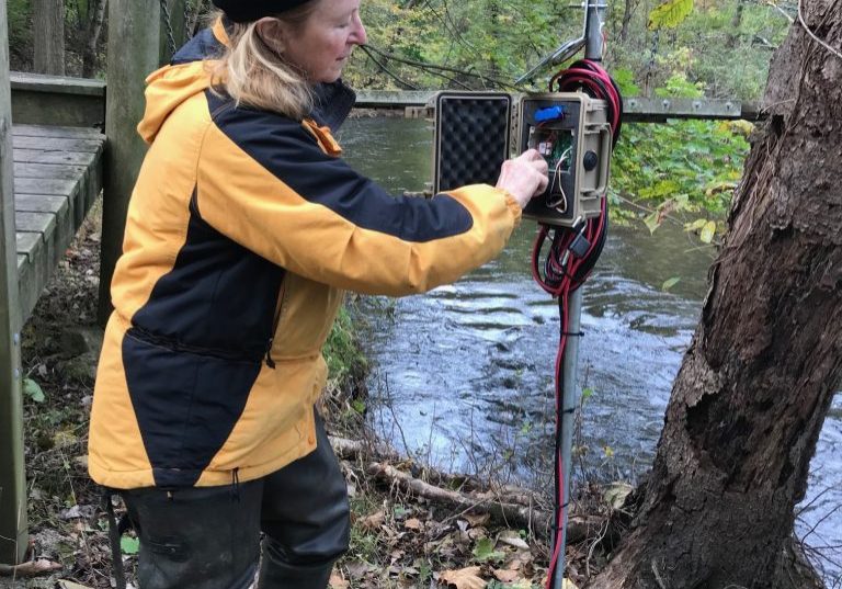 Stroud Water Research Center volunteer Carol Armstrong performs maintenance on a stream monitoring station in Pickering Creek in October 2018. Photo courtesy of Stroud Water Research Center