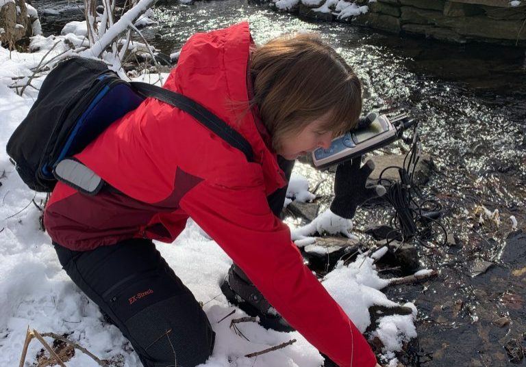 After a snowstorm in January 2025, Stroud Water Research Center scientist Jan Battle collects chloride and conductivity data from the East Branch of White Clay Creek, a Chester County stream in the Delaware River watershed. Photo: Stroud Water Research Center
