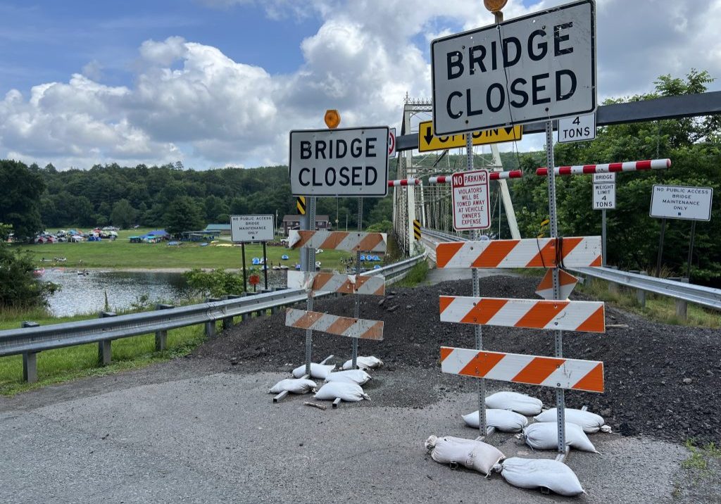 Two "Bridge Closed" signs with yellow warning lights stand at one end of the Skinners Falls Bridge.