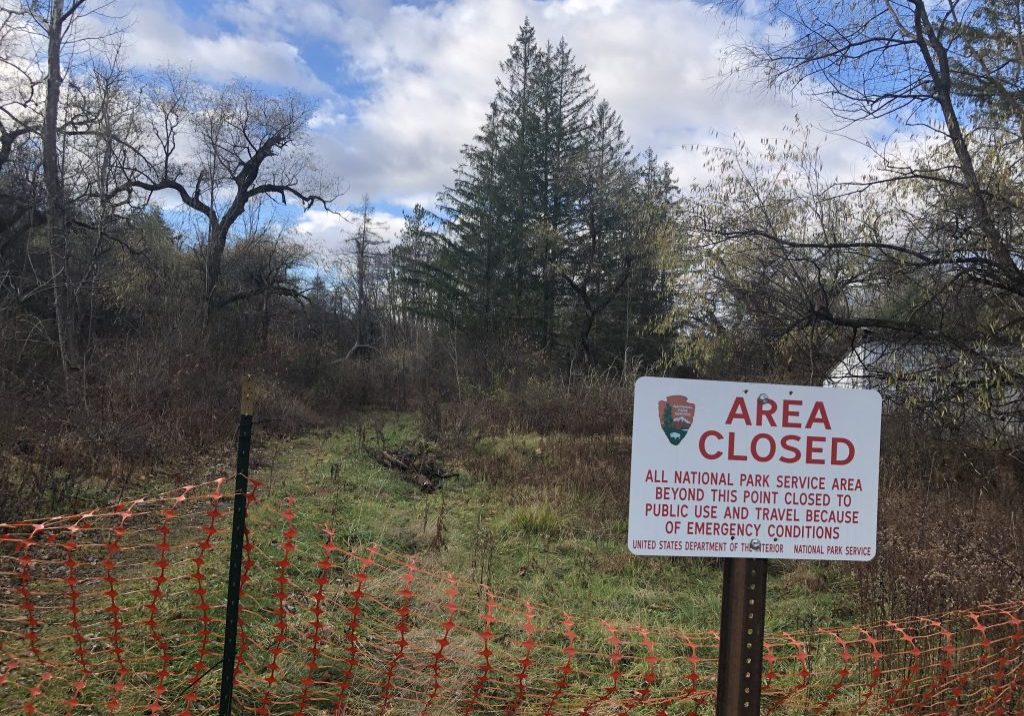 An area closed sign near an orange snow fence.
